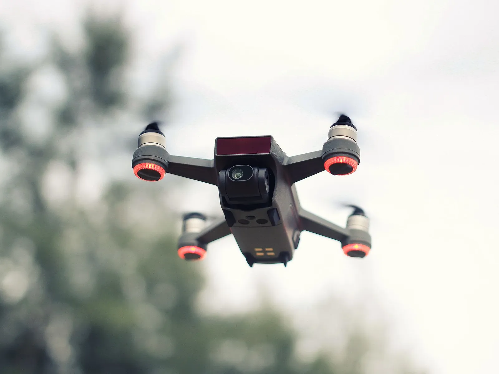 Quadcopter drone in flight against a blurred forest backdrop